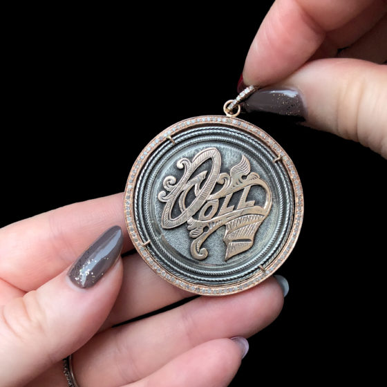 An extraordinary Victorian era love pendant token by Heavenly Vices! This one says 'Doll,' and has rose gold accents.